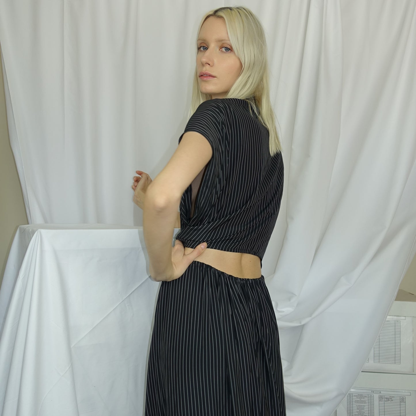 Woman in a black and white pinstripe cupro dress with an adjustable waist and button detailing