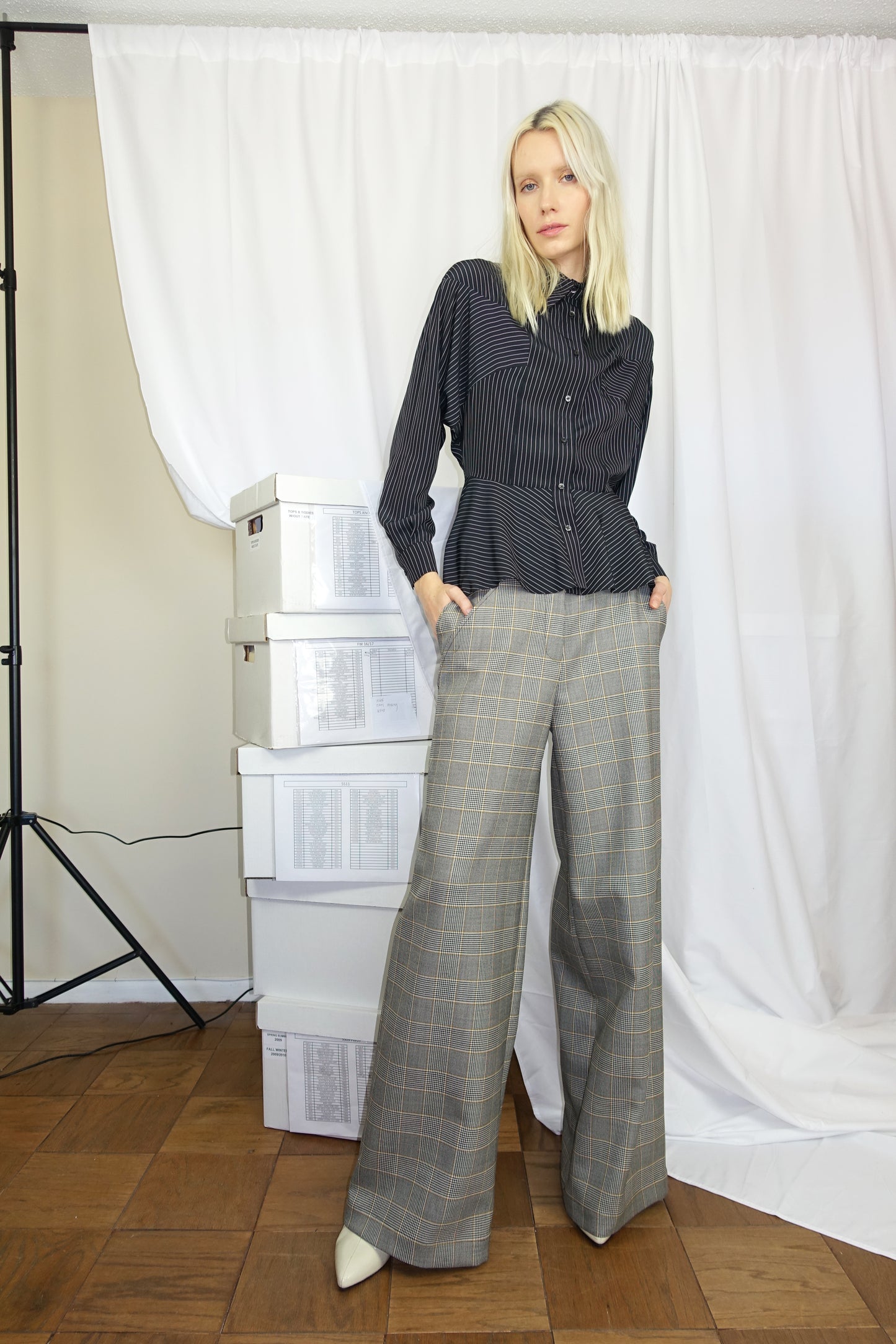 Woman wearing black and white striped cupro blouse along with gray plad pants