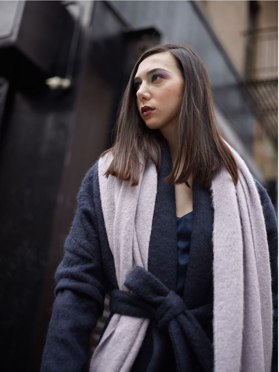 Woman wearing a navy alpaca wool and mohair coat with self-tie belt with a gray scarf