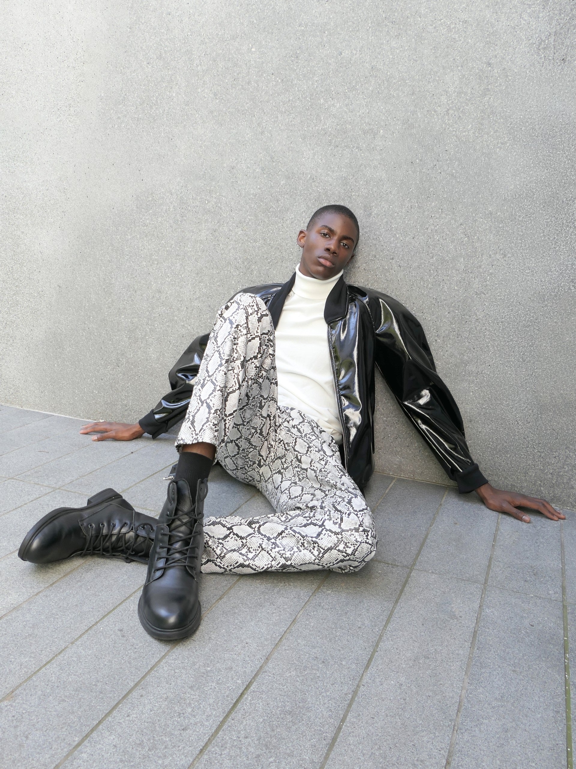 A man wearing a patent barrel sleeved jacket sitting on the floor with white geometric pattern pants and black combat boots.

Credits:
Photographer/Stylist: Nikko Kefalas @nikkokefalas
Jacket: @heike_ny