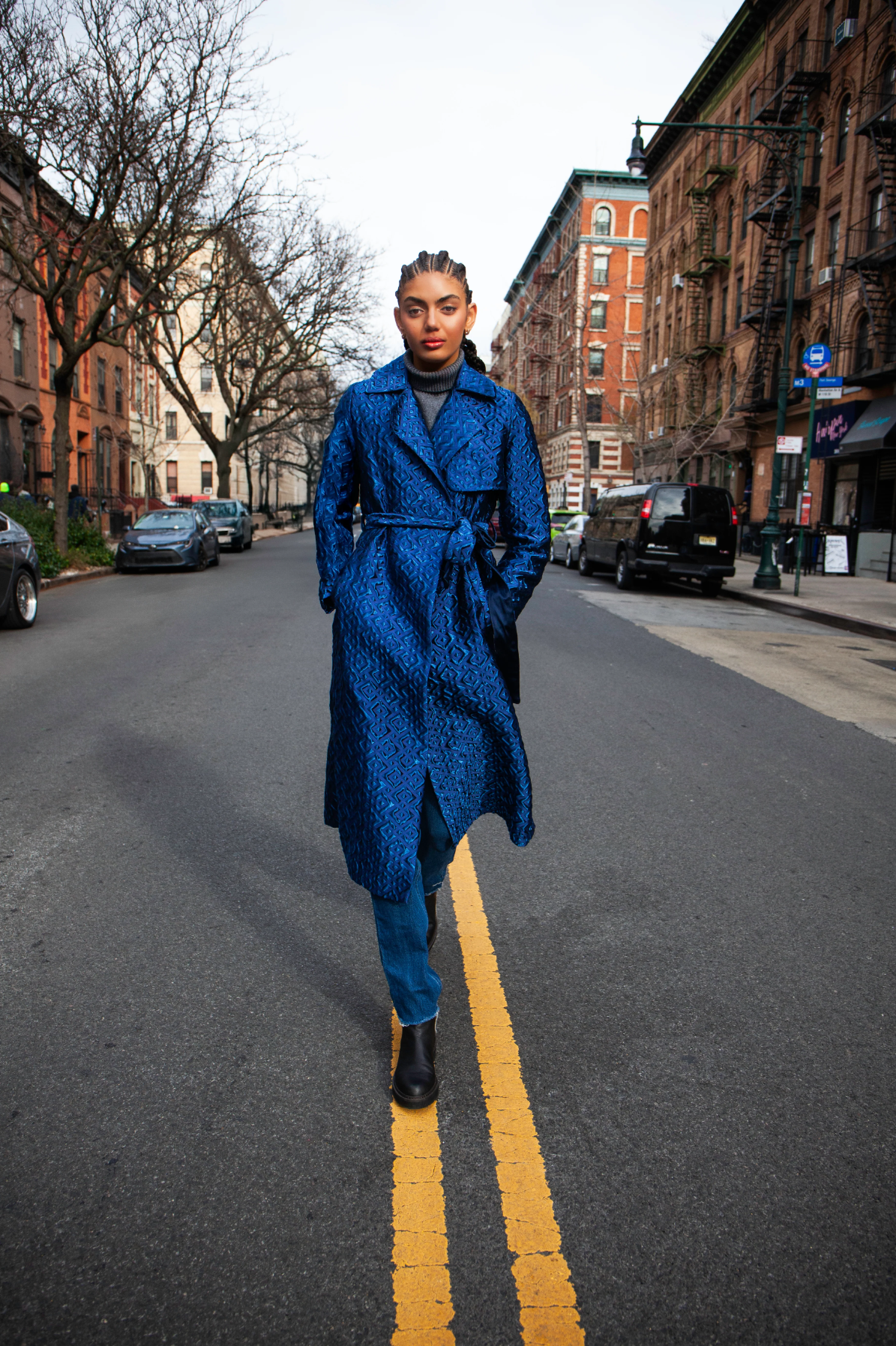 Woman wearing long blue coat with geometric patterns and a tie belt, standing in the middle of a street.

Photographer: @swatters Designer: @heike_ny Model @leianeilson