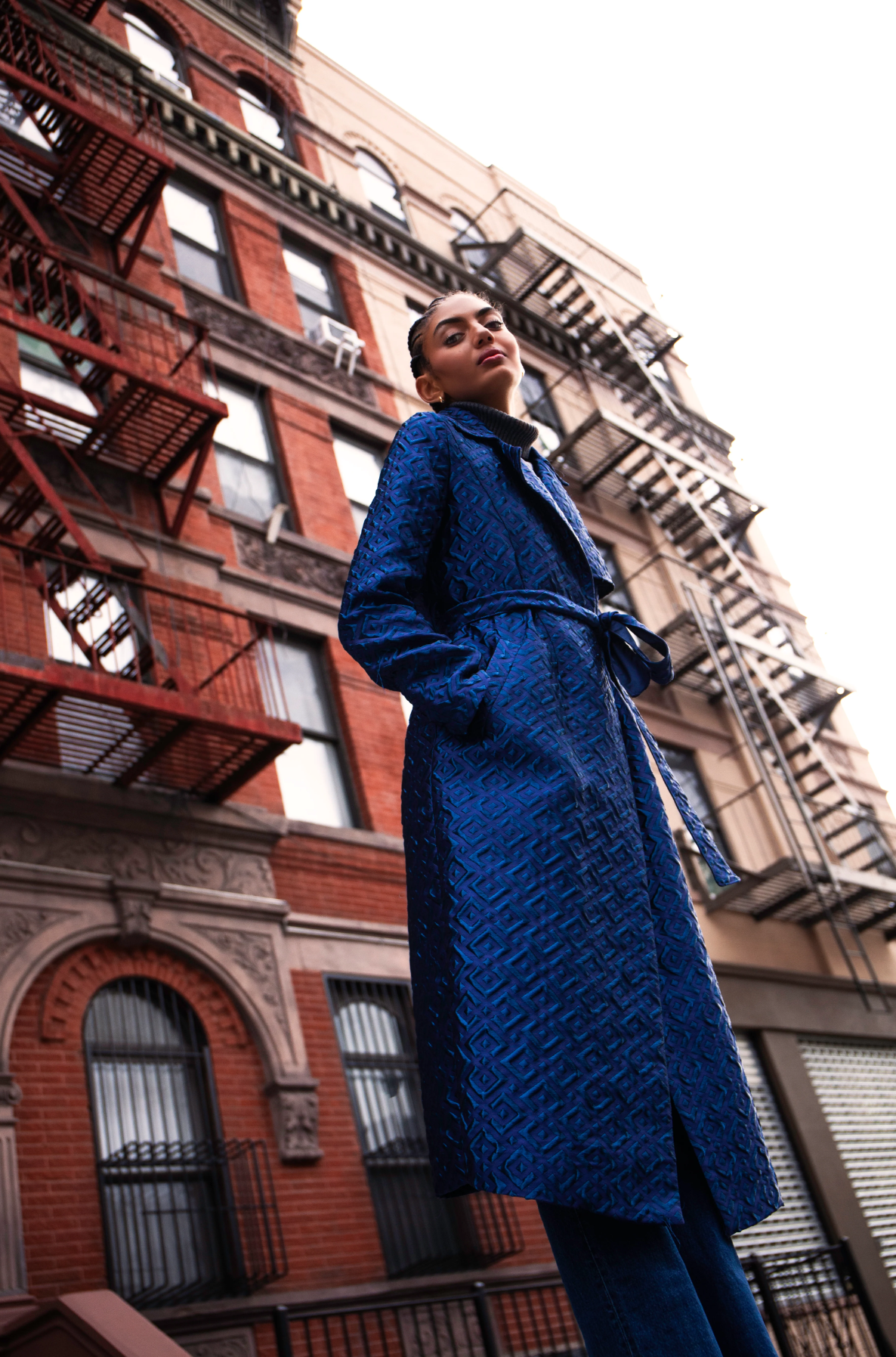 Woman wearing long blue coat with geometric patterns and a tie belt, standing in front of an apartment building.

Photographer: @swatters Designer: @heike_ny Model @leianeilson