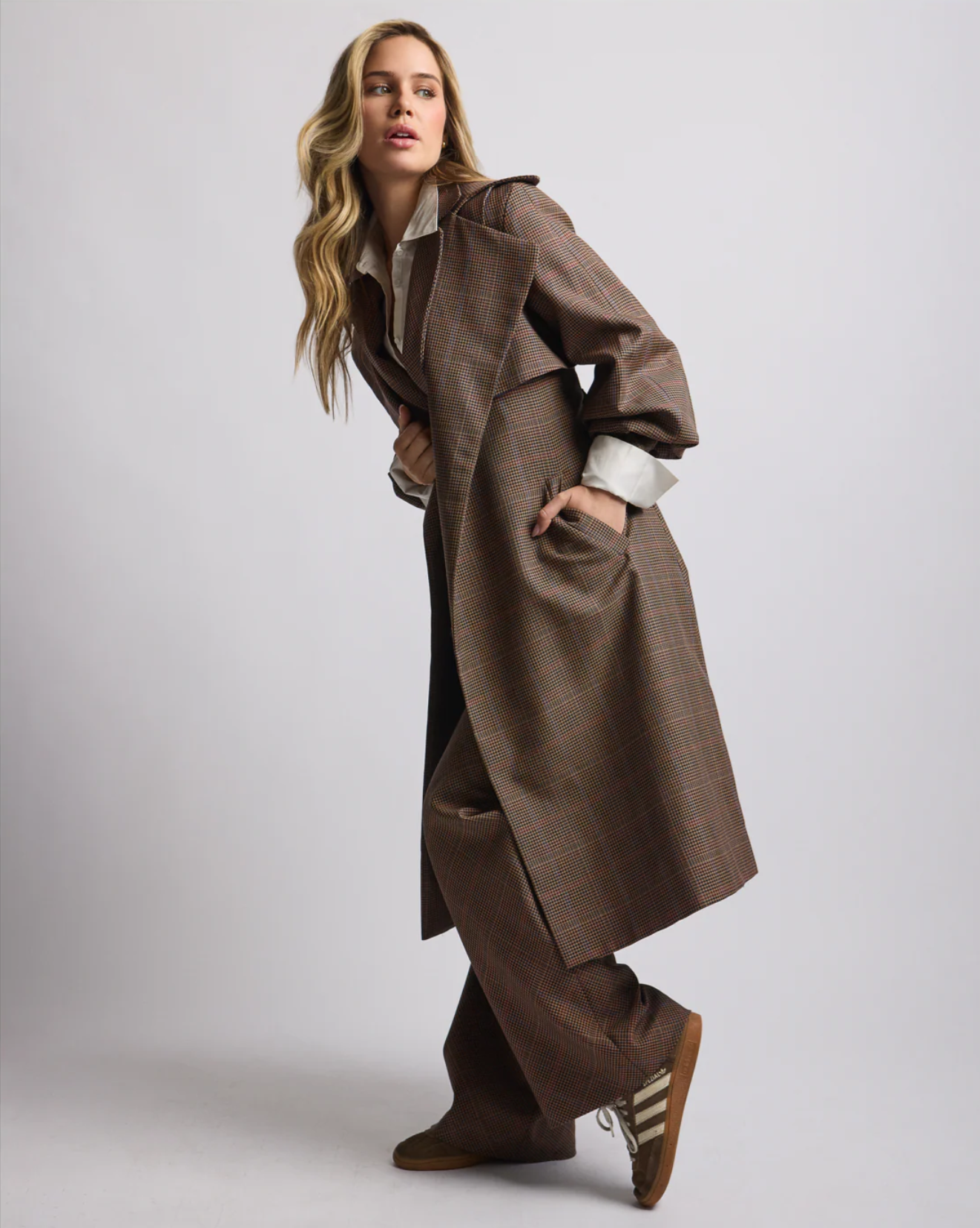 Woman wearing plaid trench coat with matching brown trousers posing with one foot slightly up.

Credits: Photographer: @lalotorre Stylist: @styledbynikolett
Designer: @heike_ny