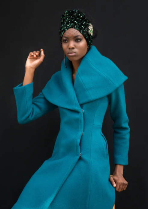 Woman wearing long teal coat with a cape collar, holding one hand up.

photographer Sean P. Watters @swatters creative hair, Mua and styling by @ecoconyc modeled by the gorgeous @francescaoyeleke