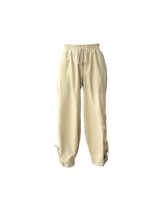 Beige drawstring pants with a relaxed, baggy fit and adjustable cuffs